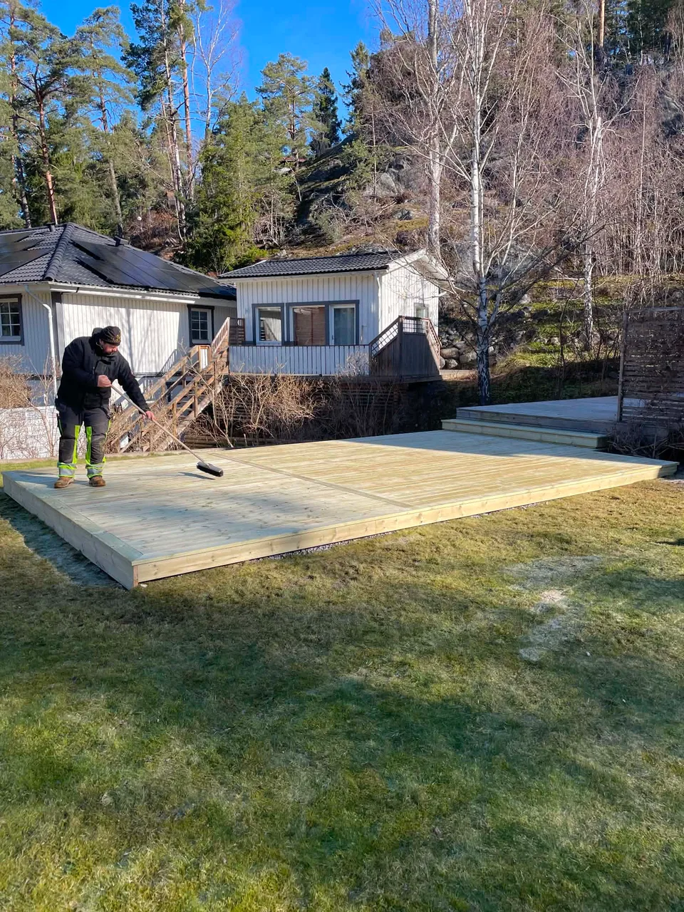 Färdigbyggt trädäck där trallen är lagd och ytan sopas ren
